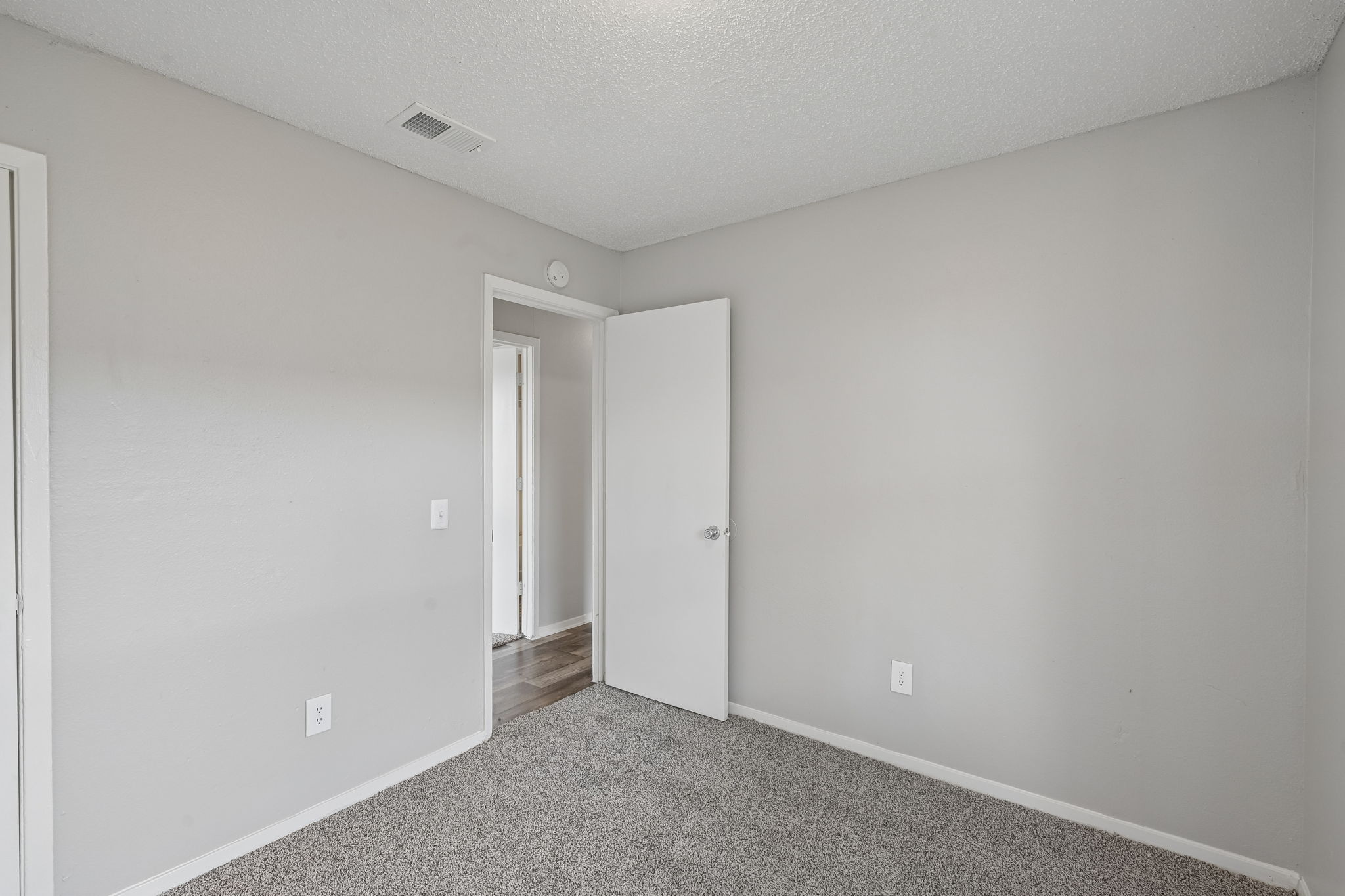 A room with a carpeted floor and a white door.